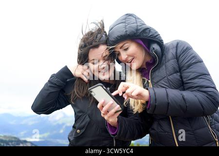 female hikers using smartphone on mountain top to orientate digitally Stock Photo
