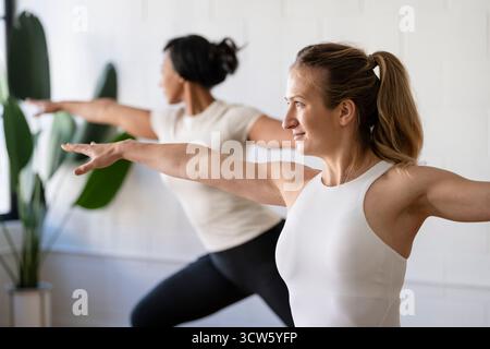 Two women practicing yoga poses during class Stock Photo