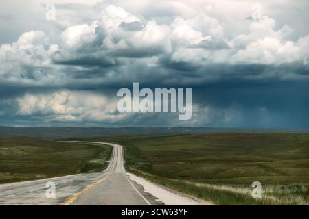 Long Empty Highway leading to Rainclouds in Distance Stock Photo