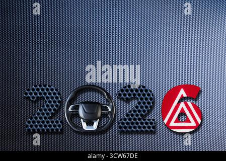 Modern 2026 text made of dark carbon fiber texture with car symbols and metallic design. Stock Photo