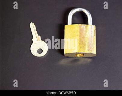 A bronze-colored lock and a key next to it on a black background, a security concept, as well as a concept of cybersecurity and data protection, with Stock Photo