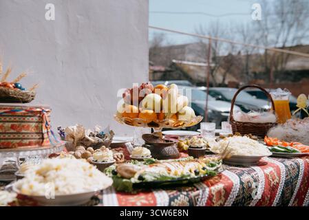 A large plate of pilaf with rice and raisins on a festive table. White rice with saffron and raisins in a plate against a bright red patterned tablecl Stock Photo