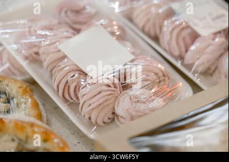 Pink marshmallows in plastic packaging with a blank label. A close-up of rows of pink packaged marshmallows or pastilles in a store Stock Photo