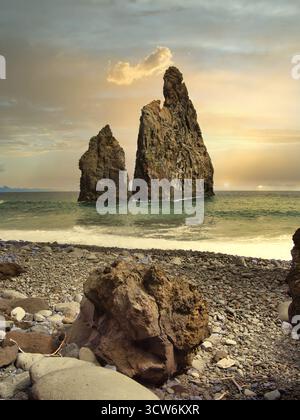 Golden Sunset Over Madeira's Sea Stacks - Atmospheric view of the Ilhéus da Ribeira da Janela volcanic sea stacks in Madeira at sunset, with a golden Stock Photo