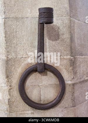 Rustic Antique Iron Ring on Stone Wall - Vertical close-up of a heavy, textured, wrought iron ring (or 'ferro da cavallo') used for tying horses, set Stock Photo