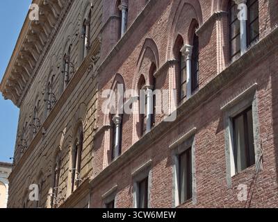 Tuscan Brick Facade with Arched Windows and Columns - Diagonal view showcasing the texture of a historic building's red brick facade and multiple arch Stock Photo