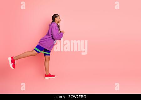 Young woman in colorful sportswear stretches dynamically on pink background showcasing active, sporty lifestyle Stock Photo
