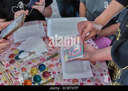 Hands, paints, and creative process. Participants creating colorful abstract patterns using the traditional Ebru water marbling technique during an ar Stock Photo
