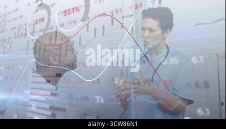 Gesturing Asian doctor in scrubs explaining financial charts in exam room, stethoscope, IV stand. Medical, consultation, healthcare, analysis, profess Stock Photo