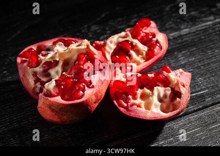 sliced pomegranate on black wood background Stock Photo