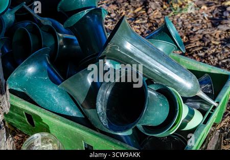 Close up of green plastic cemetery vases stacked in a box outdoors on a graveyard, used for flowers and memorial decoration. Stock Photo