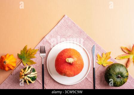 Autumn table setting with pumpkins, leaves and cutlery on beige background, festive thanksgiving dining concept. Top view, flat lay. Stock Photo