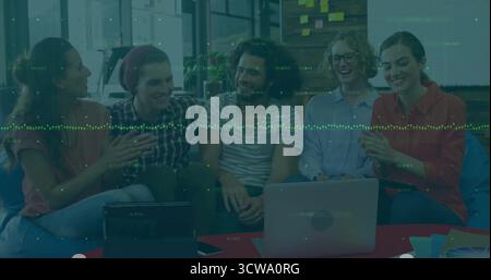 Collaborating team using laptop and tablet on table in office lounge, with sticky notes Stock Photo