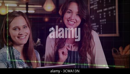 Posing central barista wearing striped apron behind cafe counter, with chalkboard menu and tablet Stock Photo
