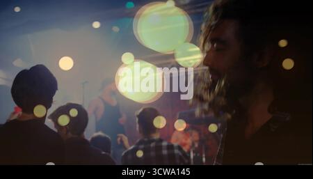 Viewing bearded man watching vocalist in small club with microphone and stage lights, copy space Stock Photo