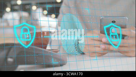 Holding smartphone man wearing shirt at desk with laptop, grid and security icons overlay Stock Photo