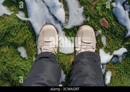 Person Standing on Grass with Melting Snow Stock Photo