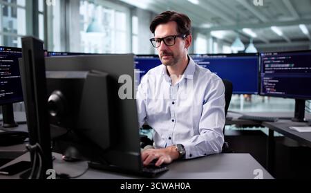 Senior Programmer Debugging Cyber Security Software At Desktop In Office Stock Photo