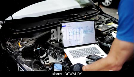 Senior Technician Uses Laptop To Diagnose Car Engine In Garage Stock Photo