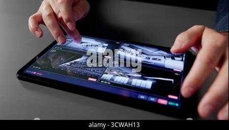 Male IT Professional Monitors CCTV Footage On Tablet At Home. Stock Photo