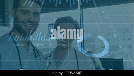 Standing two doctors in scrubs in hospital corridor, with stethoscopes, IV stand and digital charts Stock Photo