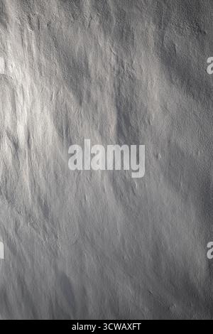 Close-up of a clean and uneven painted stone wall in black & white. Beautiful sidelight creates soft shadows. Abstract textured background, copy space Stock Photo