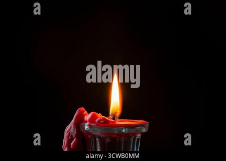 Glass candlestick with red burning candle on black background, close up Stock Photo