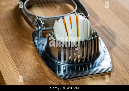 Use an egg slicer to cut a boiled chicken egg, close up. Cutting eggs into slices Stock Photo