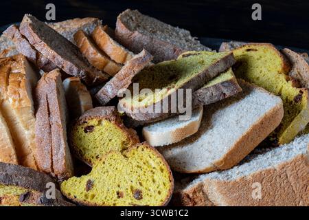 Various sliced fresh bread in a tray on the wooden table, close up. Arrangement with bakery products Stock Photo