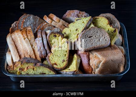 Various sliced fresh bread in a tray on the wooden table, close up. Arrangement with bakery products Stock Photo