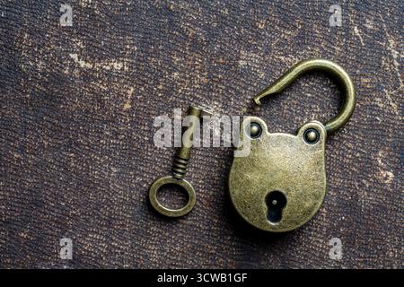 Vintage unlocked padlock and bronze key on a dark background, close up, copy space Stock Photo