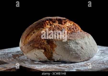 Round loaf of freshly baked sourdough bread on wooden cutting board, close up. Rustic sourdough bread. Cooking healthy sourdough bread at home Stock Photo
