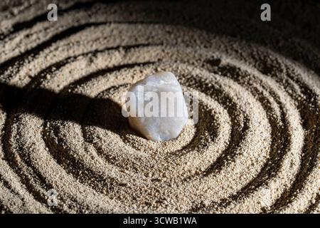 Stone, sunbeam and circles in the sand, close up. Sundial concept of meditation and tranquility Stock Photo