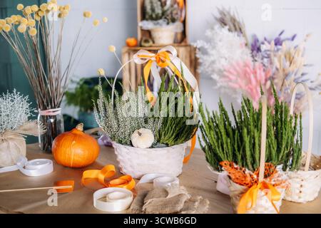 Decorated Thanksgiving table with floral gift baskets, pumpkins, and natural craft materials in a rustic setting. Seasonal centerpiece ideas, harvest Stock Photo