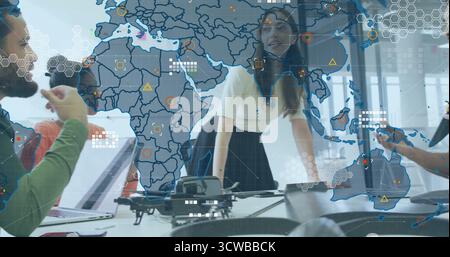 Collaborating colleagues examining drone and discussing data on digital map and laptops in office Stock Photo