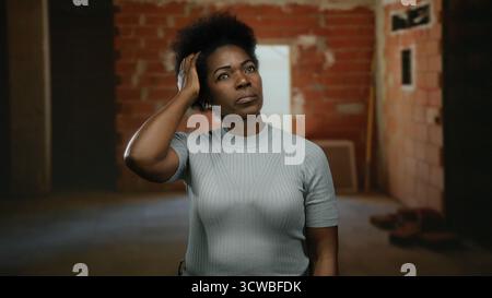 Woman contemplating in an incomplete indoor construction site wearing casual attire with a focused expression suggesting deep thought in an urban sett Stock Photo