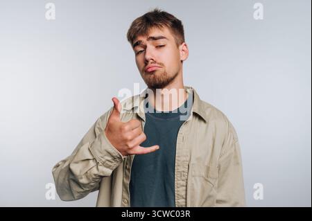 portrait of young man gives the shaka hand gesture, exuding a laid-back vibe while showcasing confidence and relaxation on white background Stock Photo