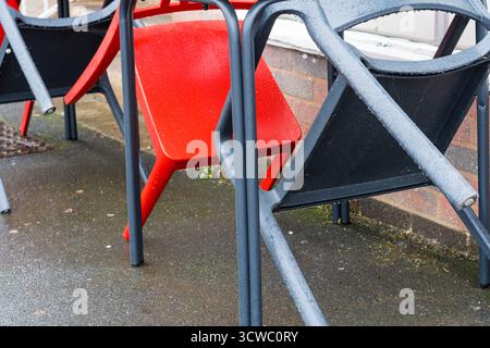 Unused chairs leaning on a table on a rainy day in autumn, UK. Stock Photo