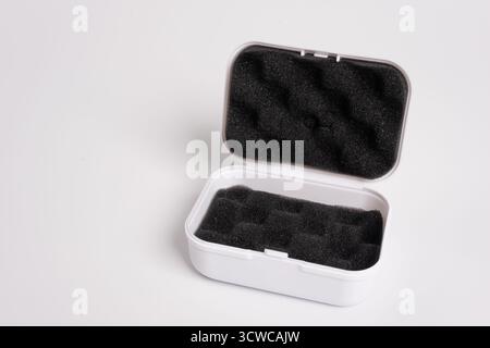White open box lined with black sponge inside, isolated on a white background. Black mini pouch bag for storing small things. Inside of the protection Stock Photo