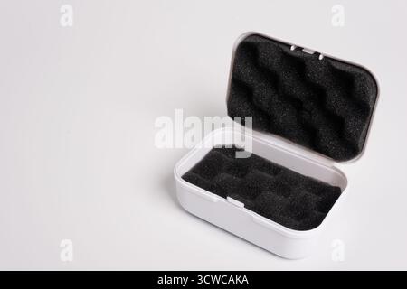 White open box lined with black sponge inside, isolated on a white background. Black mini pouch bag for storing small things. Inside of the protection Stock Photo
