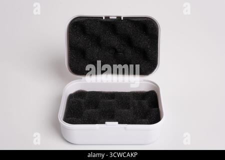 White open box lined with black sponge inside, isolated on a white background. Black mini pouch bag for storing small things. Inside of the protection Stock Photo