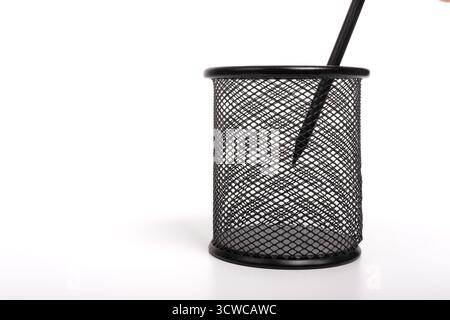 Black pen in metal pen holder on stationery stand isolated on white background. Basket paper, waste bin. Cup for pens Stock Photo