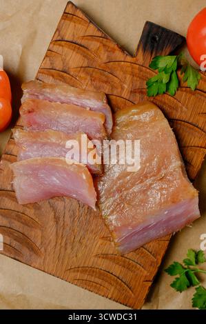 Sliced smoked or dried fish fillet on a wooden board with tomatoes. Close-up of sliced cold smoked fish with tomatoes and herbs Stock Photo