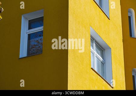 Yellow and grey contrast painted building wall lit up with bright sunlight Stock Photo