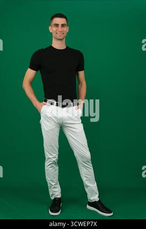 Collection of videos with fit European man in black t shirt and white pants on green chroma key background expressing various emotions smiling thinking surprised serious and confident poses. Stock Photo