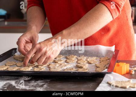 Man placing Christmas gingerbread cookies on a baking tray Stock Photo