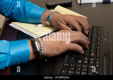 Male masculine hands type on the office keyboard entering data for the company. Stock Photo