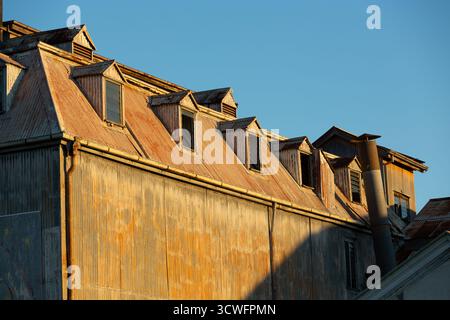 Rusting corrugated iron sheets cover the roof and walls of an abandoned industrial building in Maryborough, Queensland, Australia. The structure featu Stock Photo