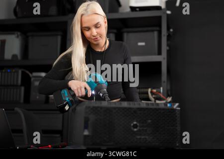 Female IT technician in a computer lab maintain and clean server hardware with a dust blower, performing maintenance Stock Photo