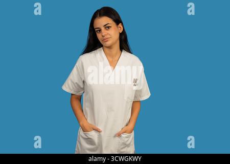 Woman healthcare worker wearing medical uniform posing with hands in pockets Stock Photo